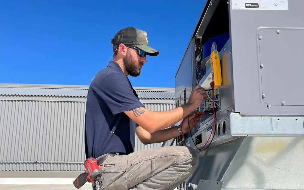 ICP rooftop package unit with its service panel open under a deep blue sky