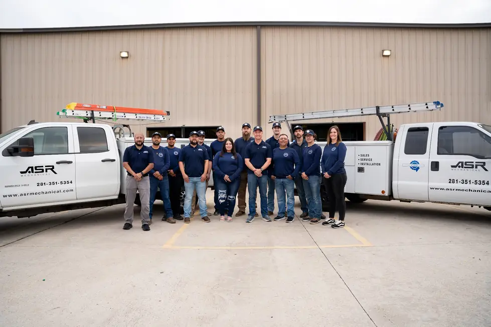 The ASR Mechanical crew lined up between two branded service trucks outside the shop