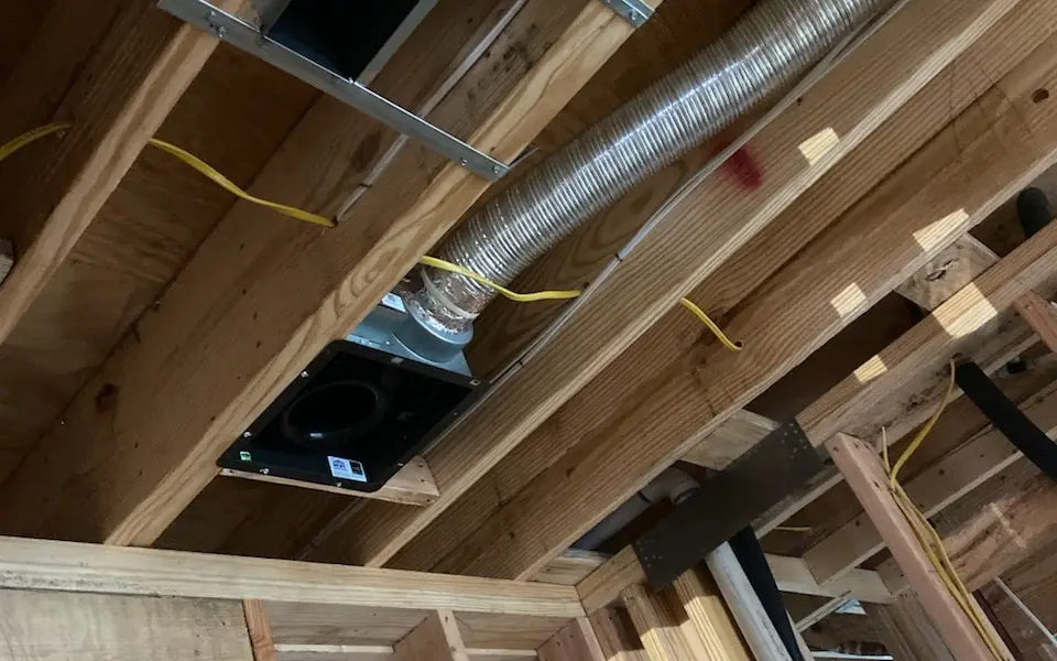 Insulated flex duct rough-in run between floor joists on a new build